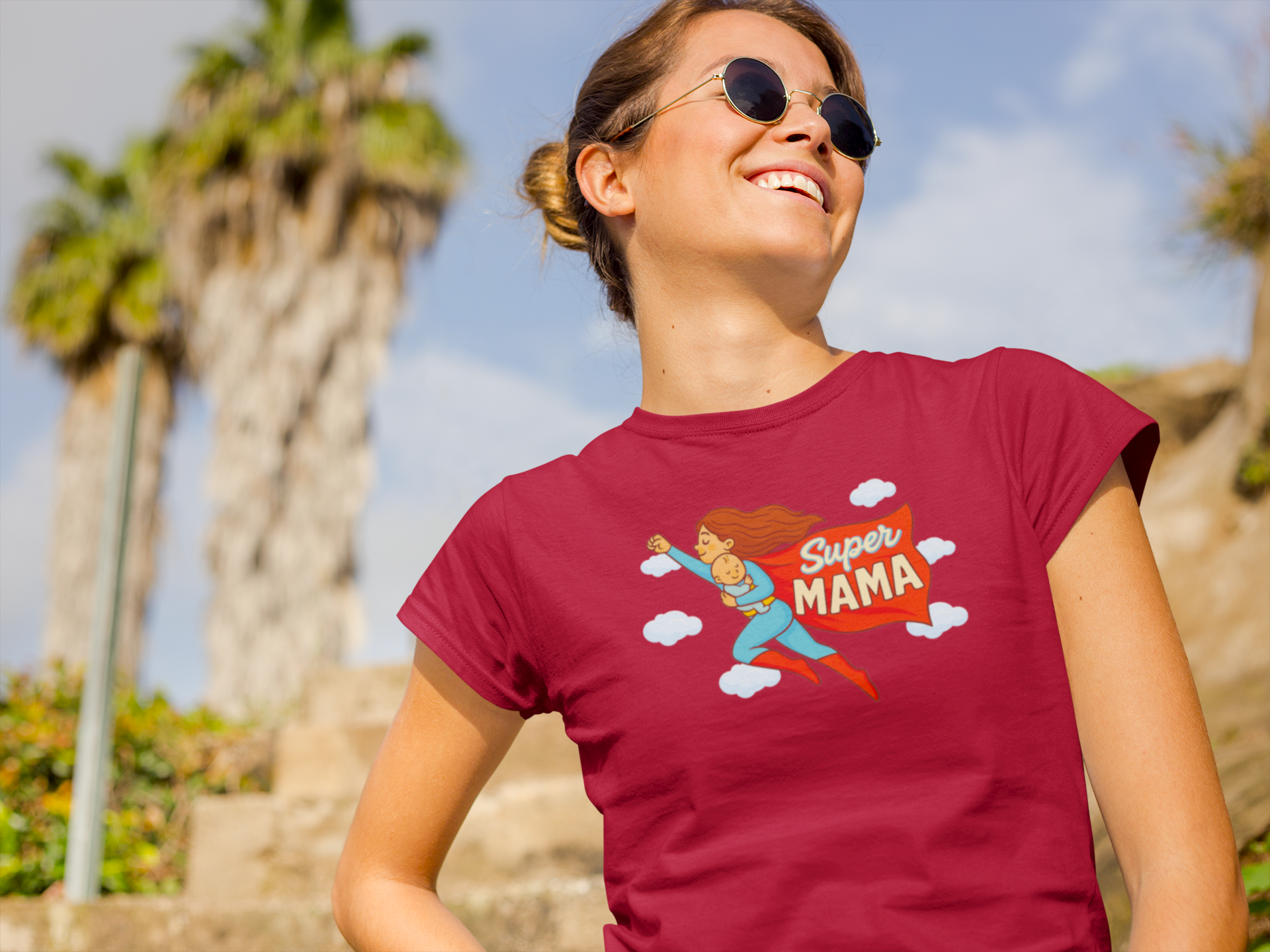 Woman smiling in cardinal red Super Mama shirt under palm trees – Mother's Day present for cool moms